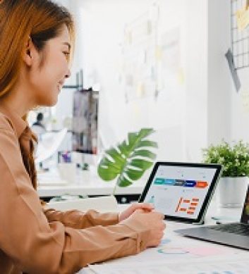 Asia businesspeople using laptop talk to colleagues discussing business brainstorm about plan in video call meeting in new normal office. Lifestyle social distancing and work after corona virus.