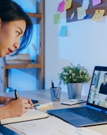 Asia businesswoman using laptop talk to colleagues about plan in video call meeting at living room. Working from house overload at night, remotely work, social distancing, quarantine for coronavirus.